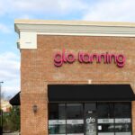 A Glo Tanning storefront with brick walls. Cloudy blue sky is behind.