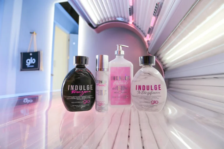 Four bottles of different tanning products are placed inside an open tanning bed.